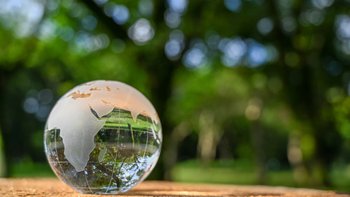 Glaskugel mit Weltaufdruck vor Naturkulisse