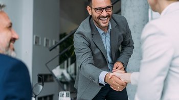 Mann schüttelt Frau Hand plus eine 3. Person / Mann beim Meeting